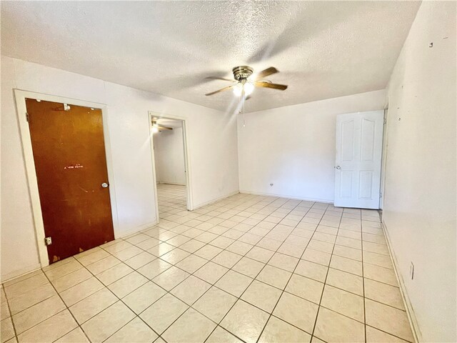 tiled spare room with a textured ceiling and ceiling fan