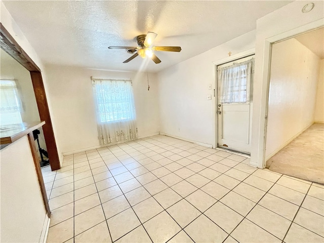 unfurnished room featuring a textured ceiling, light tile patterned floors, and ceiling fan