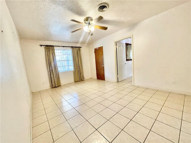 unfurnished room featuring a textured ceiling, ceiling fan, and light tile patterned floors