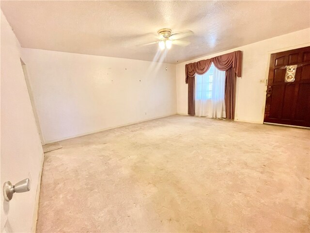 spare room featuring light colored carpet, a textured ceiling, and ceiling fan