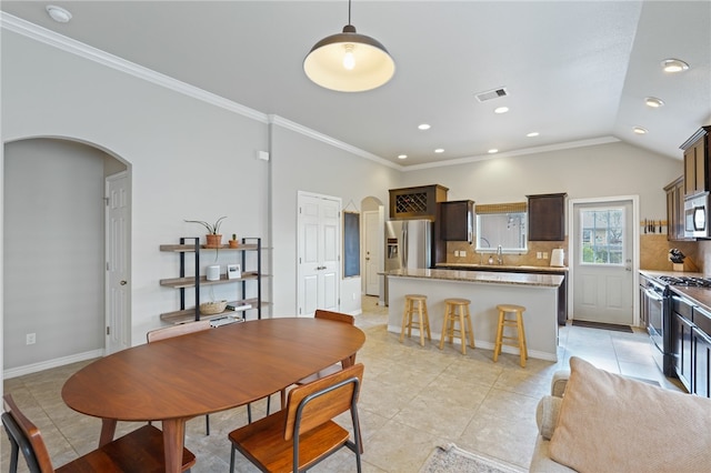 tiled dining space with vaulted ceiling, ornamental molding, and sink