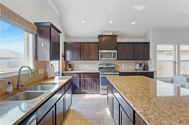 kitchen with decorative backsplash, light stone countertops, sink, and appliances with stainless steel finishes