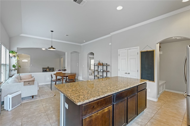 kitchen featuring light stone countertops, dark brown cabinetry, a kitchen island, and ornamental molding