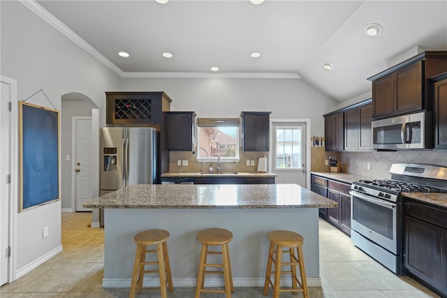 kitchen with light stone countertops, a kitchen island, and appliances with stainless steel finishes