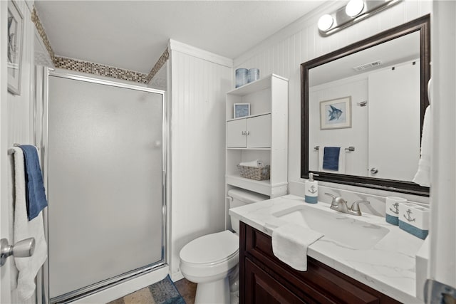 bathroom with toilet, vanity, and a shower with shower door