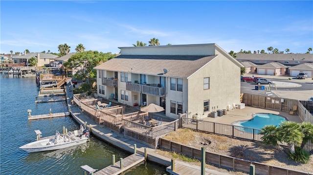 rear view of house with a fenced in pool, a patio, a water view, and a balcony