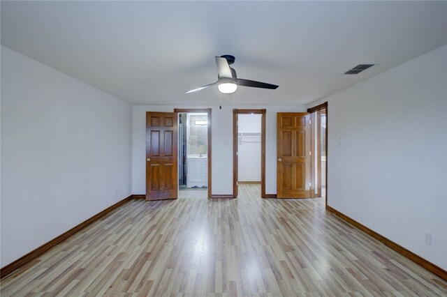 unfurnished bedroom with ceiling fan, a closet, light wood-type flooring, and a walk in closet