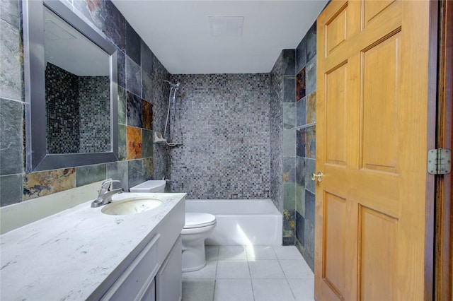 full bathroom with toilet, tile walls, tile patterned flooring, tiled shower / bath combo, and vanity