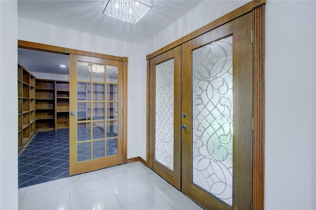 tiled entryway with french doors and a notable chandelier