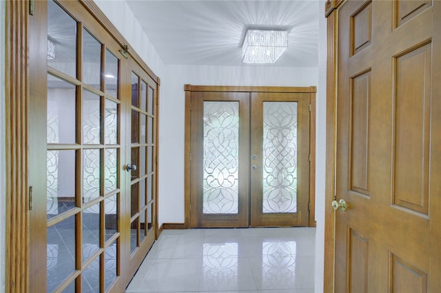 foyer featuring french doors, a notable chandelier, and light tile patterned floors