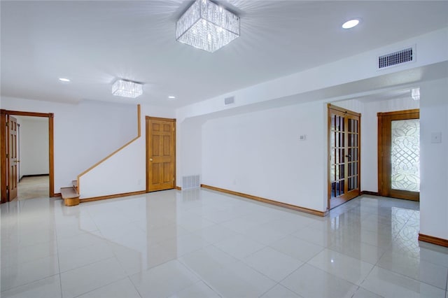 tiled spare room with a notable chandelier