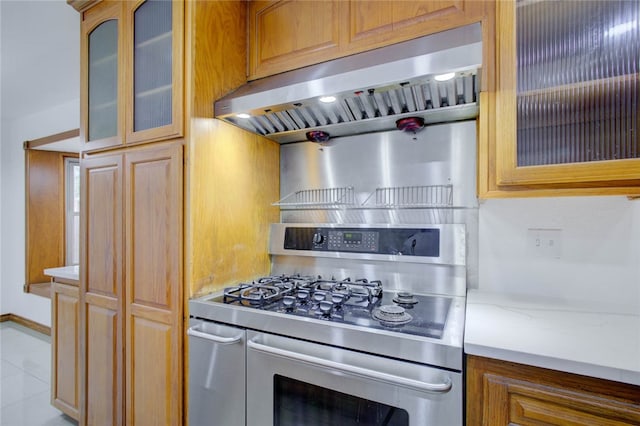 kitchen featuring ventilation hood, light stone counters, stainless steel gas range oven, and light tile patterned floors