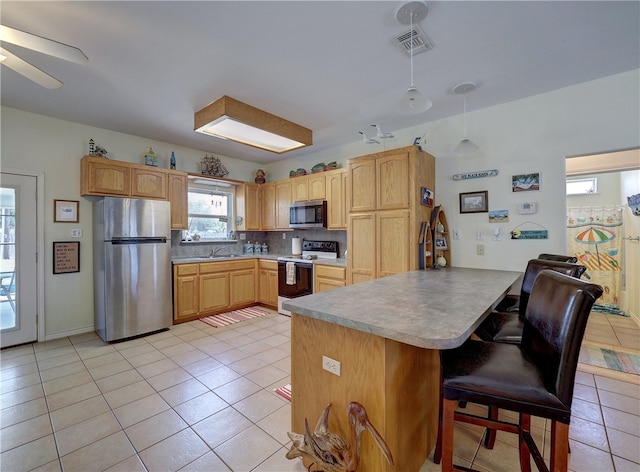 kitchen featuring stainless steel appliances, kitchen peninsula, decorative backsplash, hanging light fixtures, and light tile patterned flooring