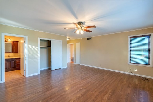 unfurnished bedroom featuring light hardwood / wood-style floors, ensuite bath, ceiling fan, and crown molding