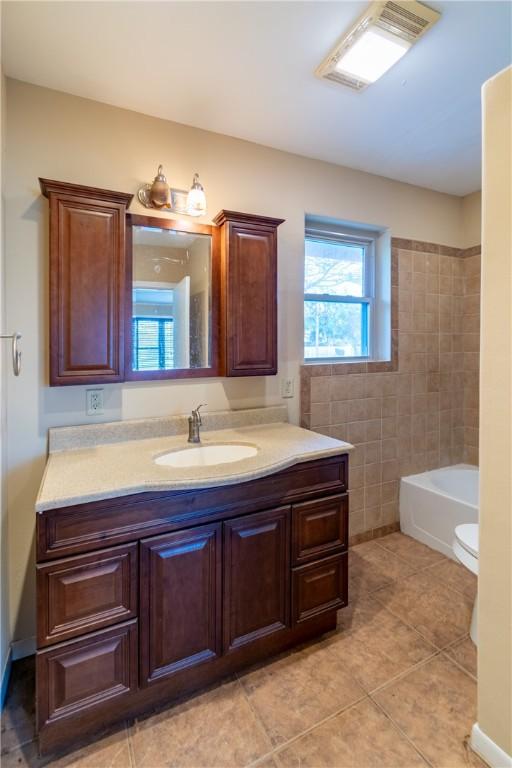 bathroom featuring tile patterned flooring, vanity, toilet, and tile walls