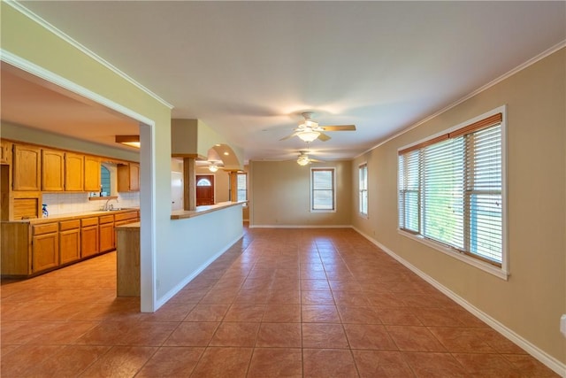 unfurnished living room with light tile patterned floors, ceiling fan, crown molding, and sink