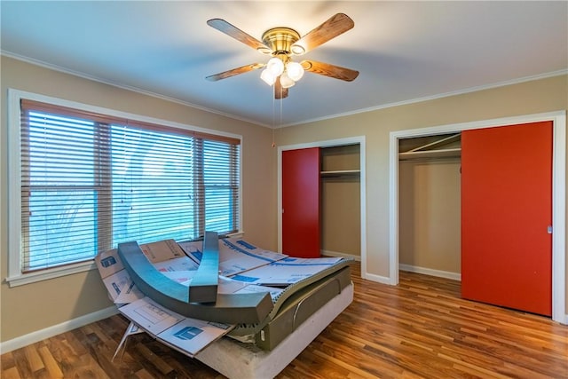 bedroom with multiple closets, ceiling fan, crown molding, and wood-type flooring