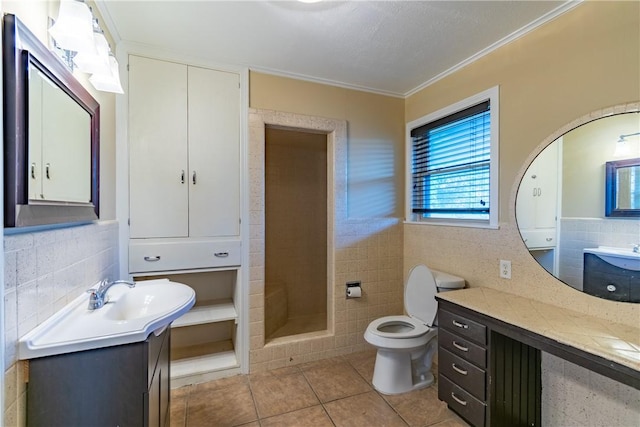 bathroom featuring vanity, tile patterned floors, toilet, ornamental molding, and tile walls