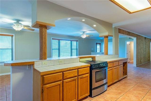 kitchen with range with electric cooktop, tile counters, a healthy amount of sunlight, and ornamental molding