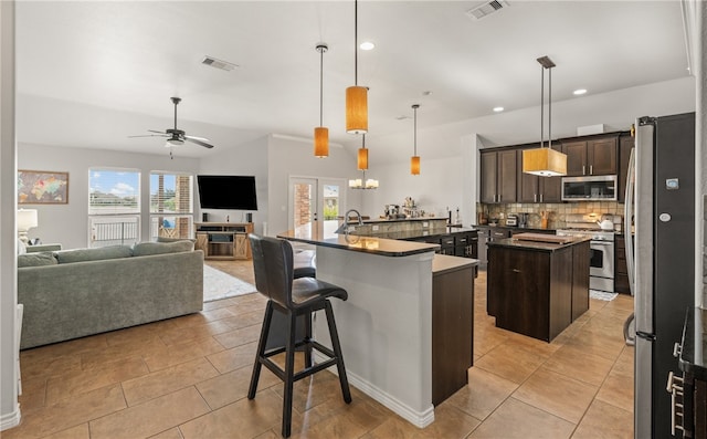 7502 Stampede Dr, Corpus Christi, TX 78414 - kitchen featuring appliances with stainless steel finishes, a kitchen island with sink, dark brown cabinets, tasteful backsplash, and open floor plan
