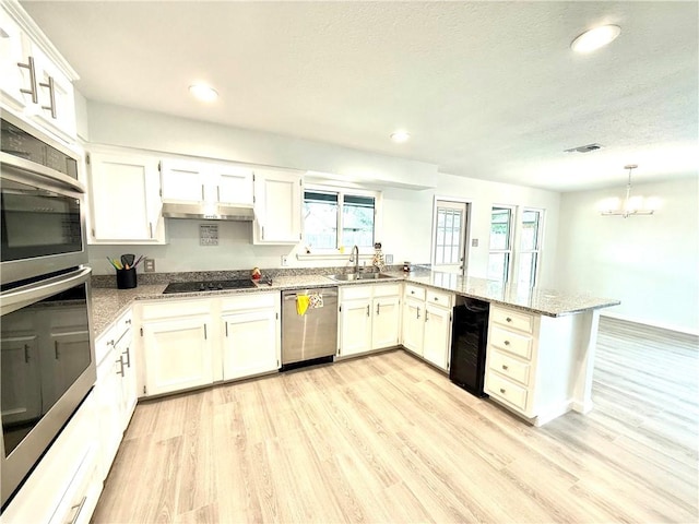 4126 Crenshaw Dr, Corpus Christi, TX 78413 - kitchen featuring appliances with stainless steel finishes, a peninsula, light wood-style floors, light stone counters, and a chandelier