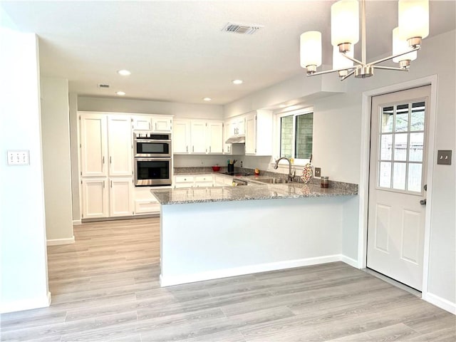 4126 Crenshaw Dr, Corpus Christi, TX 78413 - kitchen featuring double oven, light stone countertops, a chandelier, a peninsula, and white cabinetry