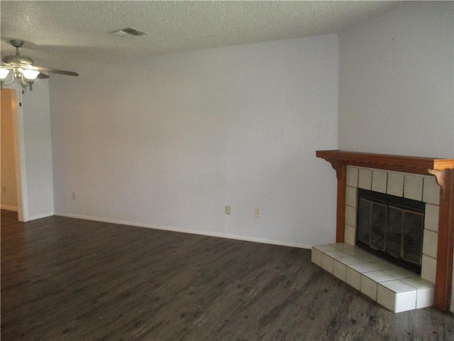 unfurnished living room featuring a tiled fireplace, ceiling fan, a textured ceiling, and hardwood / wood-style flooring