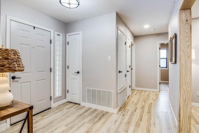 foyer with light wood-style flooring, visible vents, and baseboards