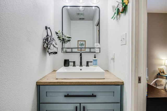 bathroom with a textured wall and vanity