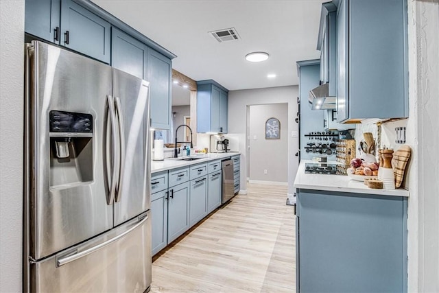 kitchen with light countertops, appliances with stainless steel finishes, a sink, and visible vents