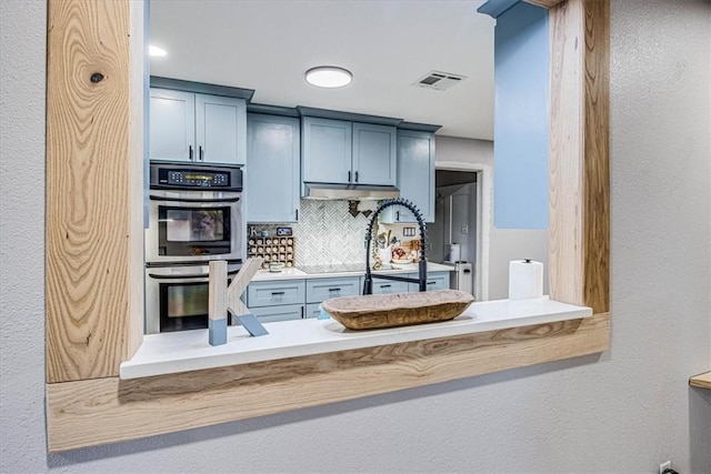 kitchen featuring tasteful backsplash, light countertops, visible vents, stainless steel double oven, and blue cabinets