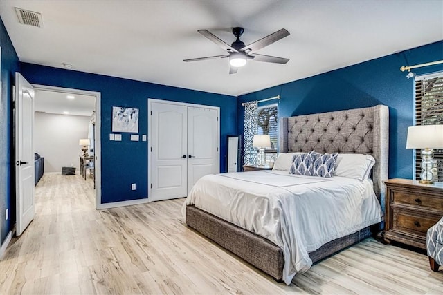 bedroom with light wood-style floors, multiple windows, visible vents, and a closet