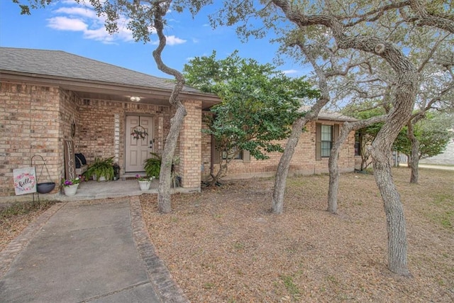 exterior space with brick siding and roof with shingles