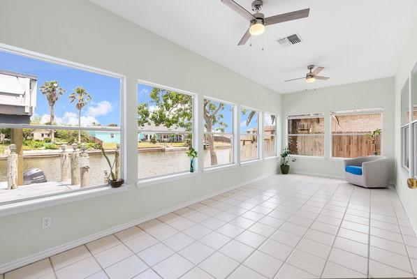 14154 Cutlass Ave, Corpus Christi, TX 78418 - unfurnished sunroom with ceiling fan, tile patterned flooring, and a water view