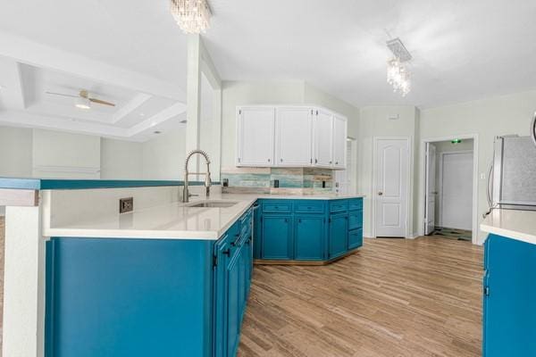 14154 Cutlass Ave, Corpus Christi, TX 78418 - kitchen with blue cabinetry, a peninsula, light wood-style flooring, light countertops, and refrigerator