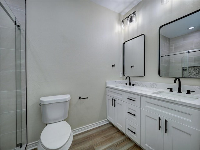 bathroom featuring vanity, toilet, a shower with door, and wood-type flooring