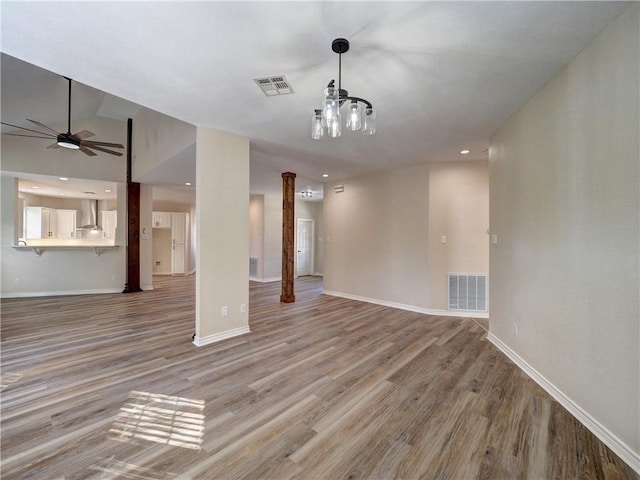 unfurnished living room with decorative columns, light hardwood / wood-style flooring, ceiling fan, and lofted ceiling