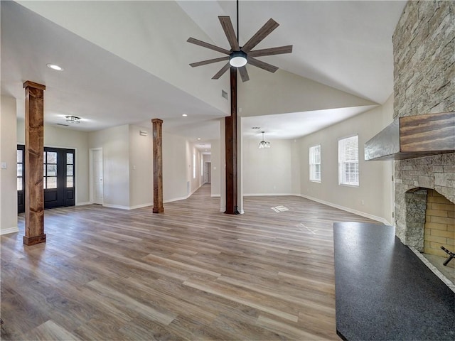 unfurnished living room featuring hardwood / wood-style floors, lofted ceiling, french doors, ceiling fan, and a fireplace