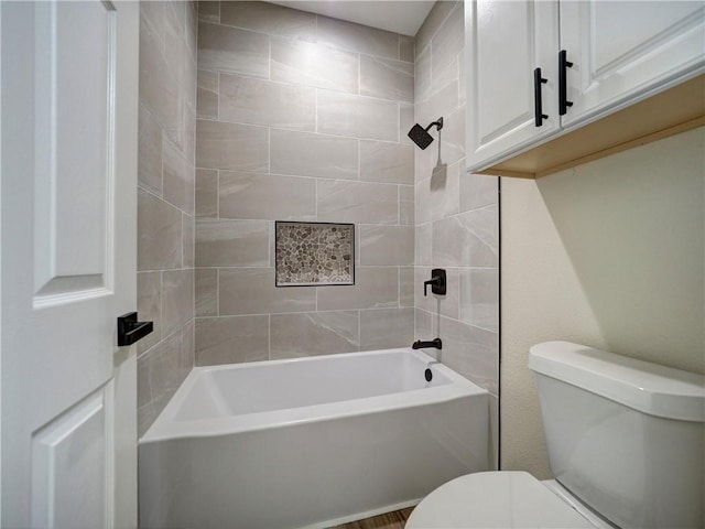 bathroom featuring tiled shower / bath combo and toilet