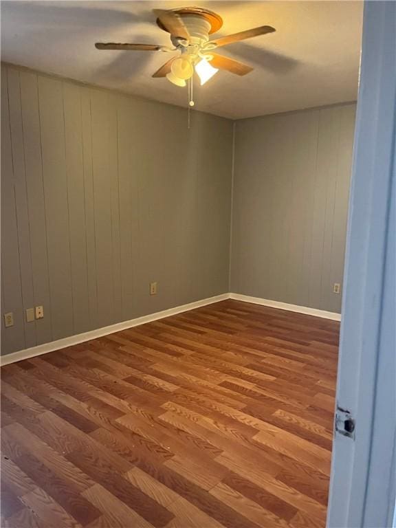 spare room featuring a ceiling fan, baseboards, and wood finished floors