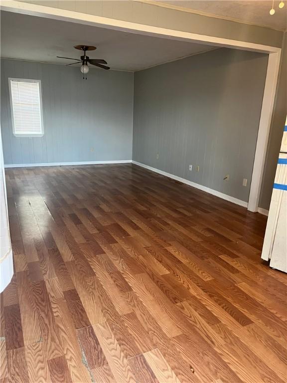 empty room with ceiling fan, baseboards, and wood finished floors