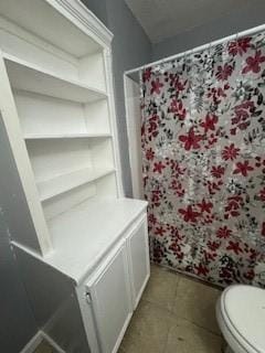 full bathroom featuring toilet, a shower with curtain, and tile patterned flooring