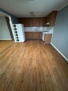 kitchen with wood finished floors, baseboards, light countertops, freestanding refrigerator, and range