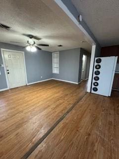 unfurnished living room with ceiling fan, a textured ceiling, baseboards, and wood finished floors