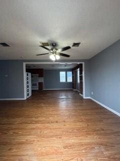 unfurnished living room with a ceiling fan, visible vents, baseboards, and wood finished floors