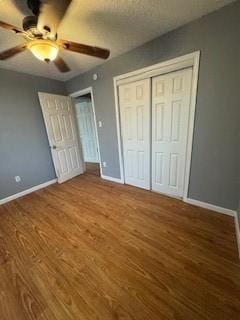 unfurnished bedroom featuring a closet, ceiling fan, baseboards, and wood finished floors