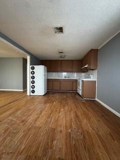 kitchen with freestanding refrigerator, a textured ceiling, wood finished floors, range, and baseboards