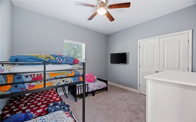 bedroom featuring light carpet, ceiling fan, a closet, and baseboards