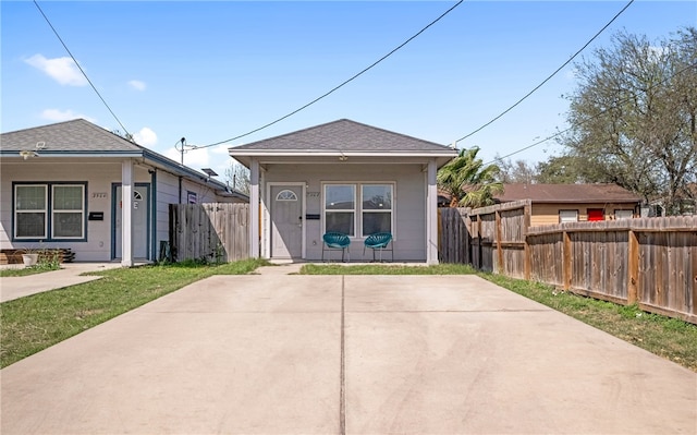 view of front of property with a shingled roof and fence