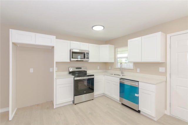 kitchen with white cabinets, sink, stainless steel appliances, and light hardwood / wood-style flooring